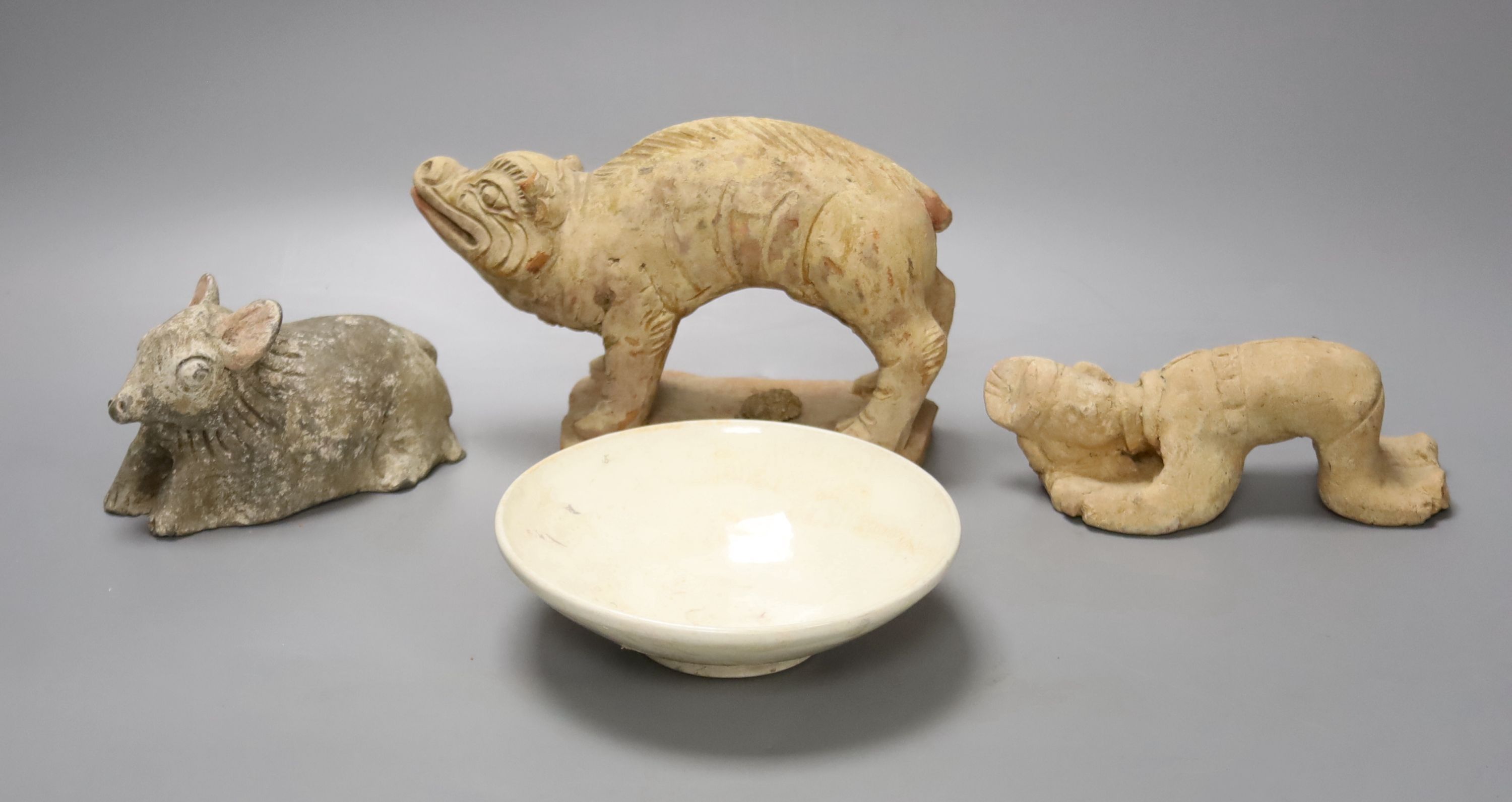 A Chinese Han terracotta model of a standing pig, 17cm long 12cm high, together with two further modelled terracotta figures and a small white glazed Chinese porcelain footed dish, diameter 14cm 4cm high